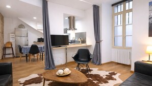 A modern living room with a dining area, a kitchen, and a large window.