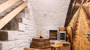 A cellar with wooden barrels, a wooden table, a bottle, and a wine rack.