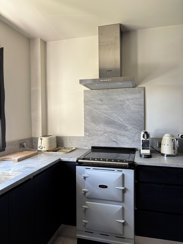 Una cocina con extractor Bosch, estufa, tostadora y hervidor.