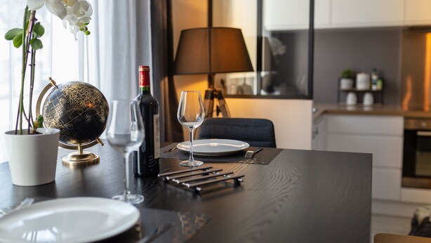 A dining table set with plates, cutlery, a wine glass, a bottle, and a globe. - SUPERB Appt DRC lorient center fully EQUIPPED  (Lorient)