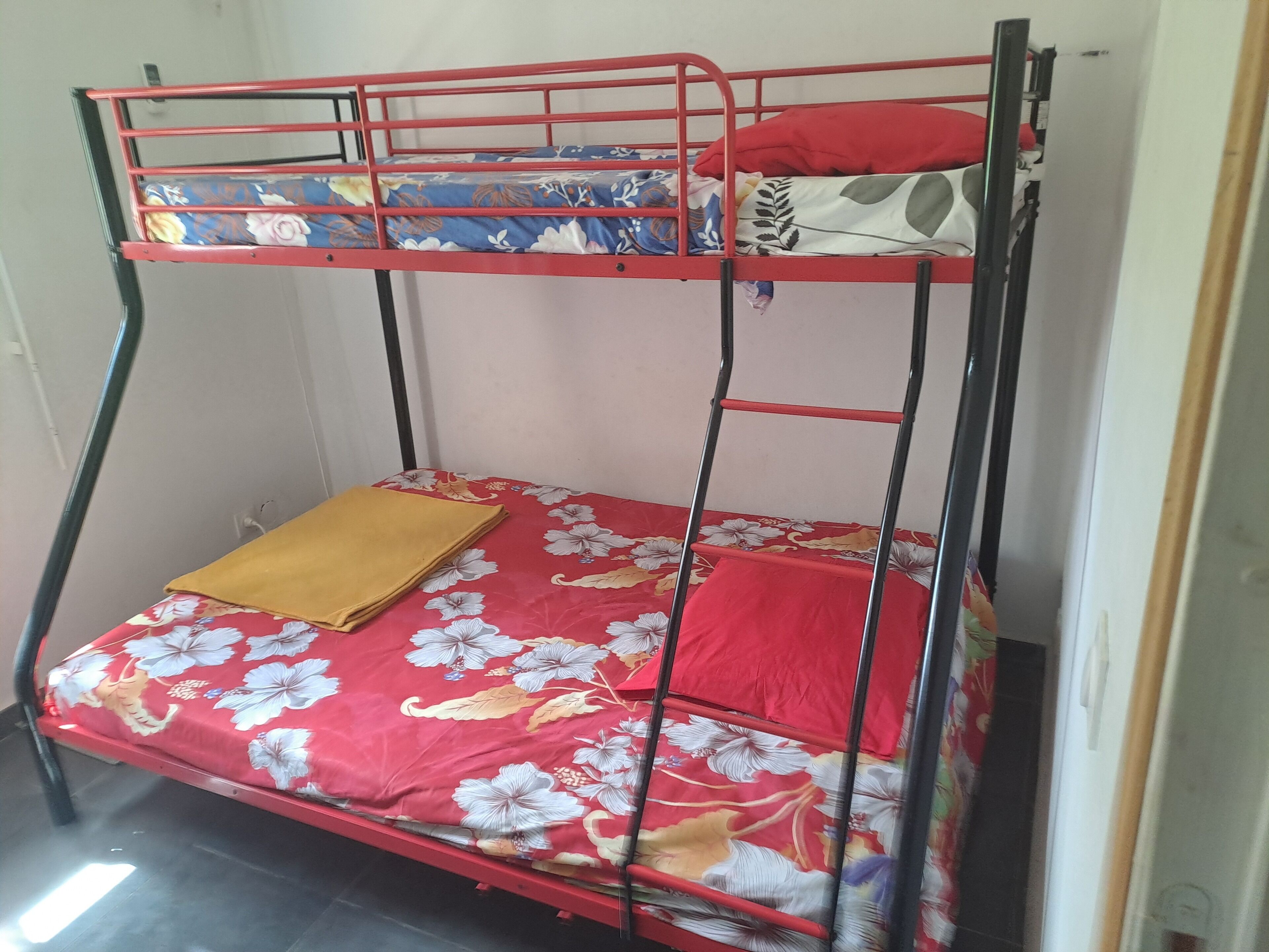 A bunk bed with a red frame and floral bedding.