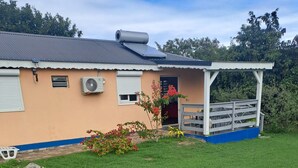A house with a sloped roof, solar panels, and a covered porch. - Damencourt bungalows Section Damencourt chemin de pinadiere 97160 le mold  (guadeloupe)