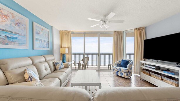 A living room with a sofa, a coffee table, a TV, and a balcony with a view. - Near Main St., Oceanfront, 6th Floor, Pools, Wifi | AshWorth - 602 (North Myrtle Beach)