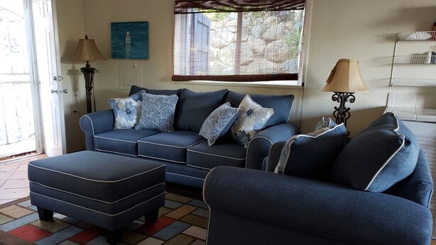 A living room with a blue sofa set, a matching ottoman, and a patterned rug. - The Cottage at Villa Indigo 2BR/1.5BA in Exclusive Private Gated Community (Saint Thomas)
