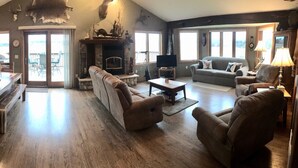 Un salon spacieux avec une cheminée, un coin repas avec une table et des chaises en bois, et un coin salon confortable avec des canapés et des fauteuils.