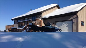 Een huis bedekt met sneeuw, met een sneeuwscooter ervoor geparkeerd.