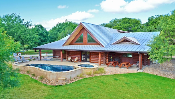 A log cabin with a swimming pool, outdoor seating, and a covered patio. - Private Pool & Hot Tub Near Lake LBJ | 3 King Bedrooms, Sleeps 13 (Burnet)