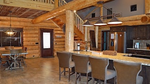 A log cabin interior with a bar area, wooden ceiling beams, and a staircase. - Private Pool & Hot Tub Near Lake LBJ | 3 King Bedrooms, Sleeps 13 (Burnet)