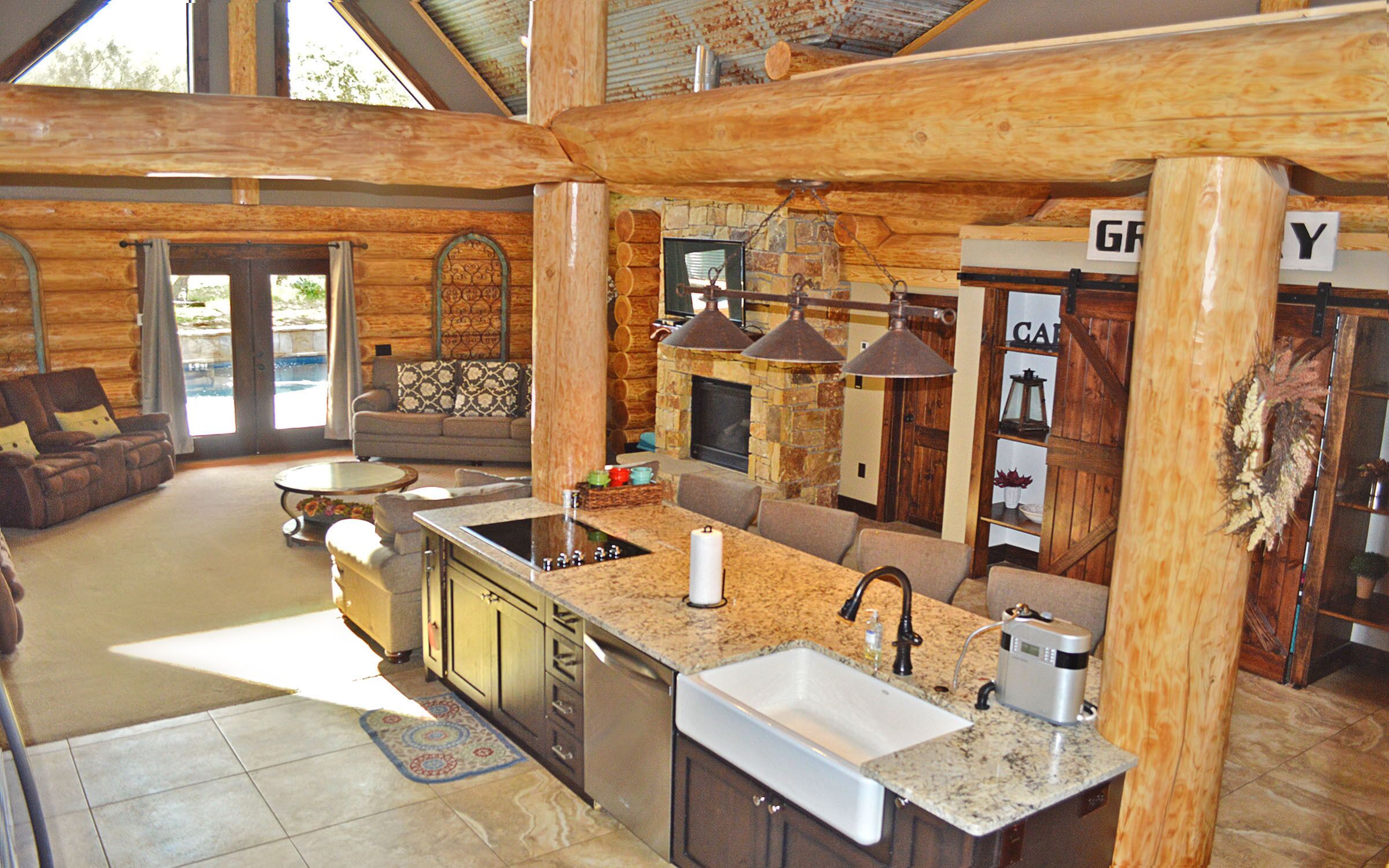 A log cabin interior with a kitchen, dining area, and a fireplace.