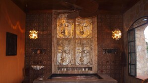 Une pièce dotée d’une grande statue de Bouddha, d’un plafond en bois et d’un mur de pierre avec une fenêtre.