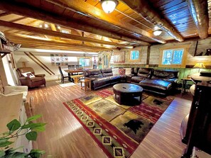 A spacious living room with a large sectional sofa, a coffee table, and a dining area with a wooden table and chairs. - 18 miles to Yellowstone Park! Golf, Snowmobile or ATV from front door! (Island Park)