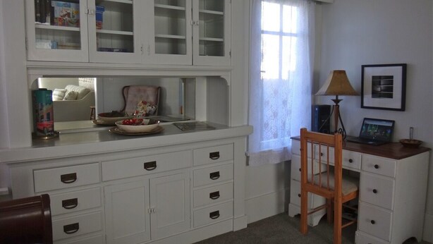 Een kamer met een witte kast met meerdere lades en een houten stoel.