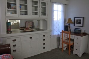 Een kamer met een witte kast met meerdere lades en een houten stoel.