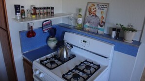 Een keuken met een witte kookplaat, een waterkoker en diverse keukenspullen op het aanrecht.