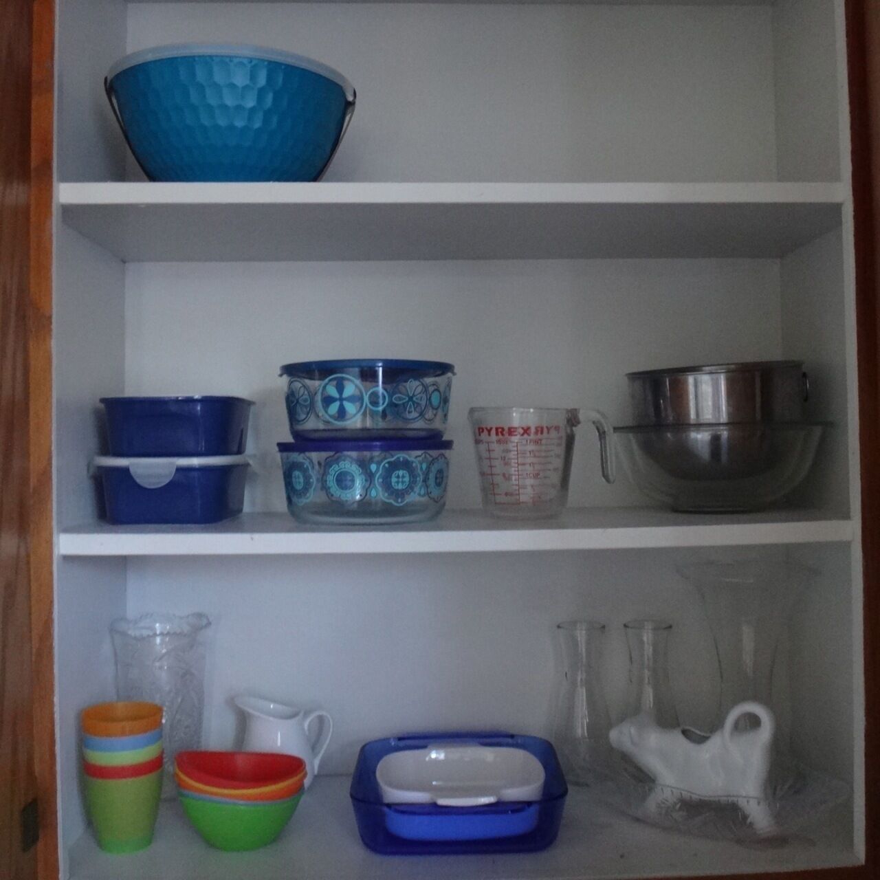 Una estantería de cocina con diversos utensilios, incluyendo tazones, tazas medidoras y recipientes.