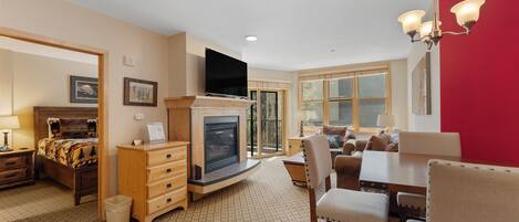 Una sala de estar acogedora con chimenea, televisor y comedor con sillas y mesa.