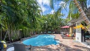 A swimming pool surrounded by lush greenery, outdoor furniture, and a modern building. - Martini Manor is the ultimate Tropical Oasis with a private Heated Pool! (Wilton Manors)