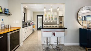 A modern kitchen with a central island, white cabinetry, stainless steel appliances, and pendant lighting. - Martini Manor is the ultimate Tropical Oasis with a private Heated Pool! (Wilton Manors)