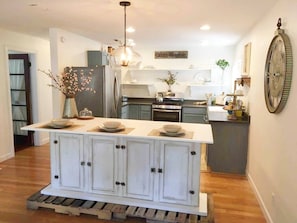 A kitchen with a central island, cabinets, and a clock on the wall.