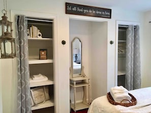 A bedroom with a bed, a mirror, a shelf with books, and a sign above the mirror.