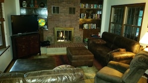A living room with a fireplace, leather sofas, a television, and a bookshelf. - Gateway To Pikes Peak, Garden Of The Gods, Manitou Springs, Old Colorado City (Colorado Springs)
