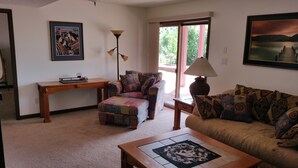 A living room with a sofa, a chair, a coffee table, a side table, a lamp, and a painting on the wall. - Gateway To Pikes Peak, Garden Of The Gods, Manitou Springs, Old Colorado City (Colorado Springs)