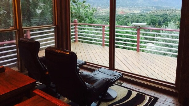 A room with a large window overlooking a deck with a red railing. - Gateway To Pikes Peak, Garden Of The Gods, Manitou Springs, Old Colorado City (Colorado Springs)