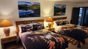A hotel room with two beds, each with mountain-themed bedding, a wooden headboard, and a nightstand with a lamp. There are two wall-mounted paintings of landscapes. - Gateway To Pikes Peak, Garden Of The Gods, Manitou Springs, Old Colorado City (Colorado Springs)
