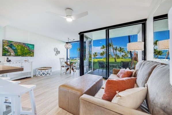 A modern living room with a large window, a dining area, and a view of the outdoors.