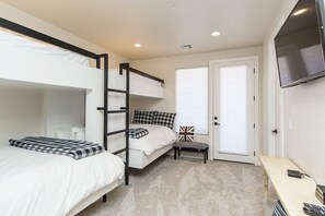A bedroom with bunk beds, a desk, a chair, a television, and a door with a window.