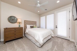 A bedroom with a bed, a dresser, a ceiling fan, and a wall clock.