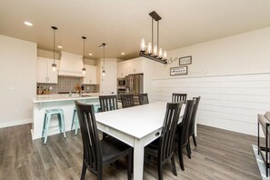 A modern kitchen with white cabinets, a central island, and a dining area with a white table and dark chairs.