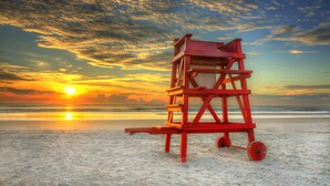 Una torre de salvavidas en una playa con un atardecer de fondo.