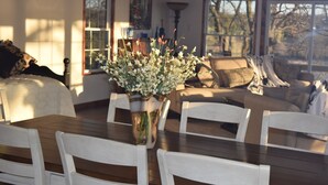 A dining area with a wooden table, white chairs, and a vase of flowers. - Allure 1900 sq waterfront home with country elegance spectacular views (Eastland)