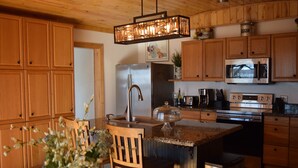 A kitchen with wooden cabinets, stainless steel appliances, a granite countertop, and a hanging light fixture. - Allure 1900 sq waterfront home with country elegance spectacular views (Eastland)