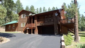 A two-story log cabin with a covered front porch, a garage, and a small deck. - Outdoor Fire Pit, Wildlife Watching, Monte Verde Lake Ponderosa (Angel Fire)