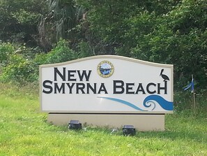 Een bord voor New Smyrna Beach, met een logo en een tekening van een vogel.