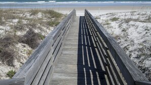 Un muelle de madera que conduce a una playa con vistas al océano.