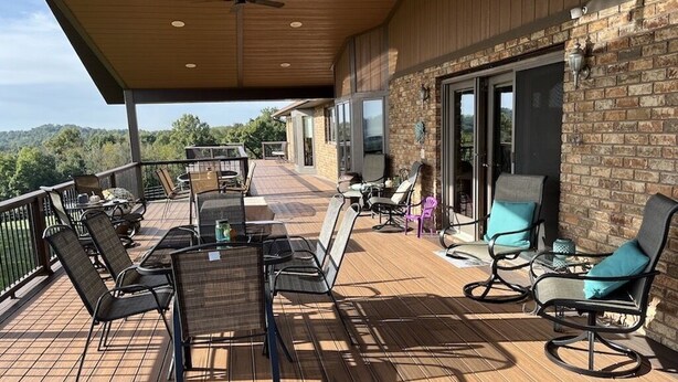 A covered outdoor deck with wooden flooring, metal-framed chairs, and a table. - Great for Friends & Families, Breathtaking View, Nature Trails, Farm Animals (Millersburg)