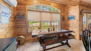 Interior de madera con un ventanal grande, un banco de madera, una mesa y un letrero de JavaJolt Coffee.