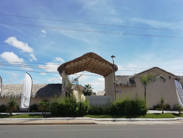 A building with a thatched roof entrance, a sign reading "LA LAGOON," and a street lamp.
