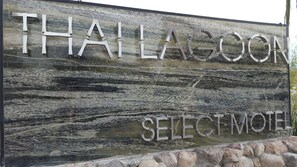 A wooden sign with the words "THAILAGOOON" and "SELECTMOTEL" indicating a motel.