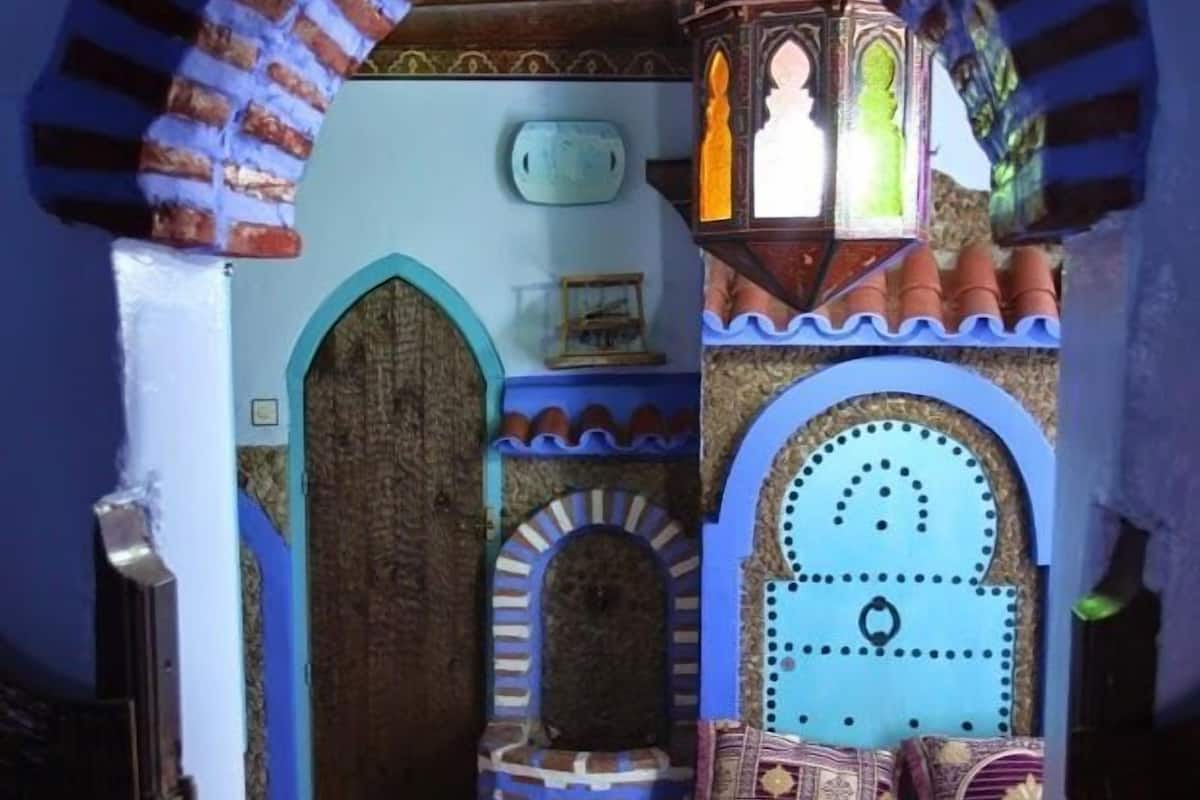 A room with a checkered floor, a wooden door, a patterned bed, and a decorative lantern.