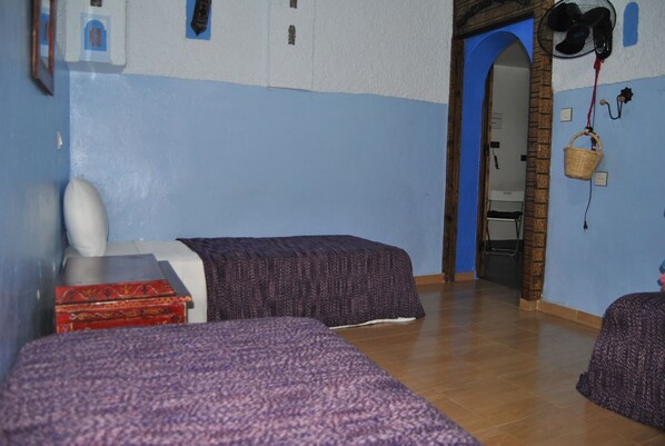 A room with two beds, a wardrobe, a mirror, and a door leading to another room. - Casa La Hiba (Chefchaouen)