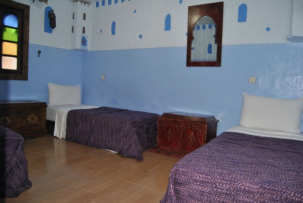 A room with two beds, a wooden dresser, and a mirror on the wall. - Casa La Hiba (Chefchaouen)