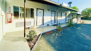 A motel with a covered parking area, multiple doors, and a fire extinguisher mounted on the wall. - Casa Blanca Inn & Suites (Whittier)