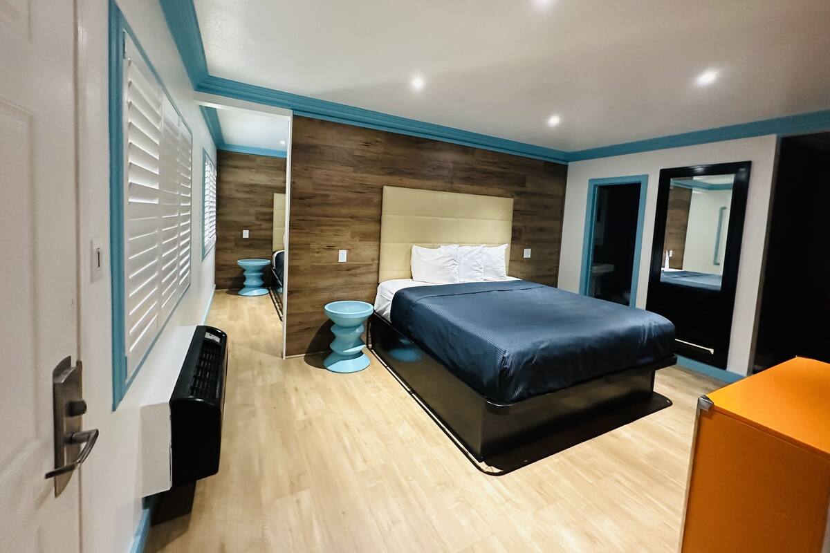 A modern bedroom with a bed, bedside tables, a wardrobe, and a bathroom visible through an open door.
