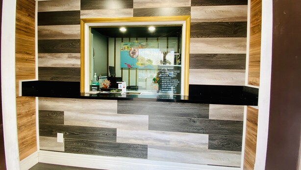 A reception area with a check-in counter, a wall-mounted security camera, and a sign listing hotel rules. - Casa Blanca Inn & Suites (Whittier)