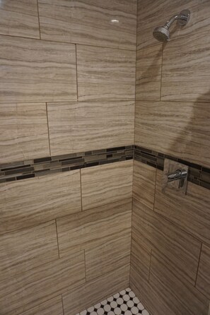 A shower area with a tiled wall and a showerhead. - Las Palmas Hotel (Los Angeles)