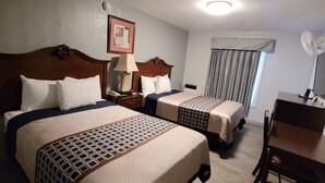 A hotel room with two beds, a desk, and a chair.